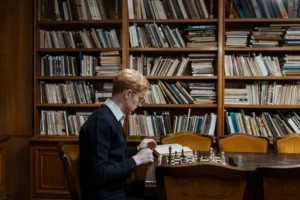 mężczyzna-znajdujący-się-w-blibliotece-planuje-kolejny-ruch-w-szachy-strategia